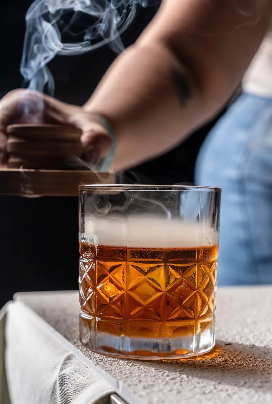 Bartender expressing citrus over a smoked cocktail